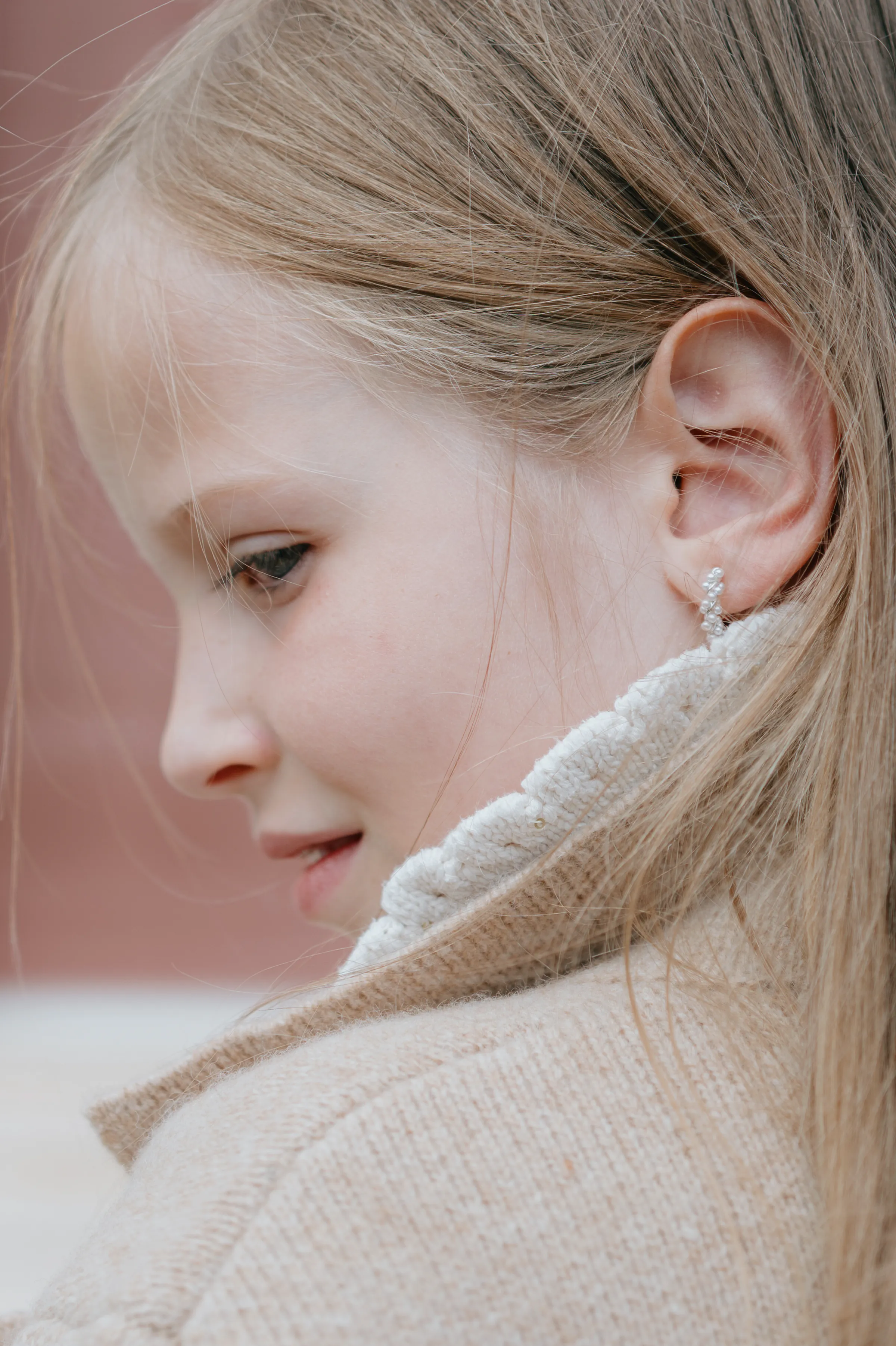 Close portrait of a child in profile, wearing a cream sweater in soft light.