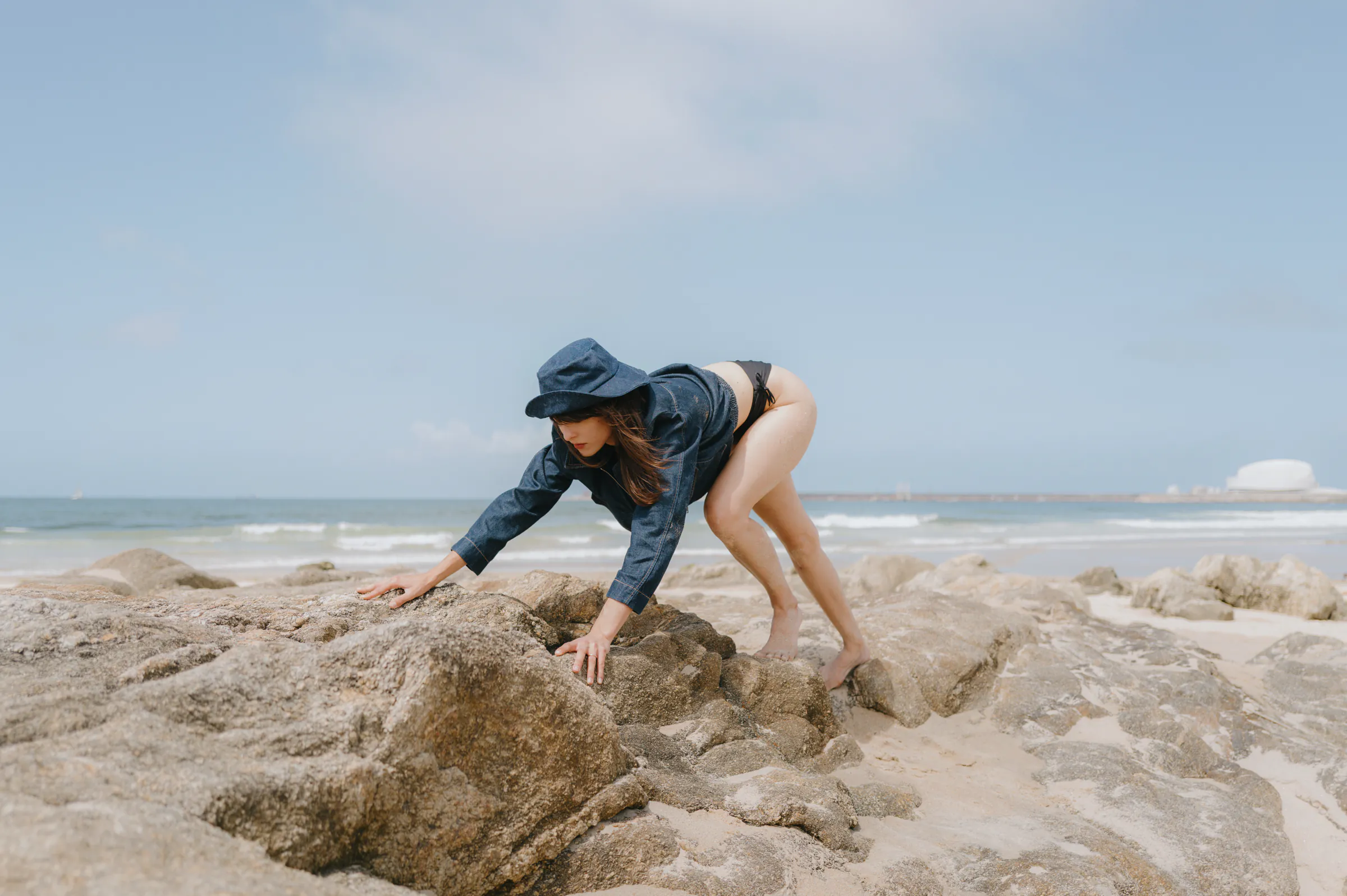 Seaside outdoor session with a person climbing across pale rocks beside the ocean.
