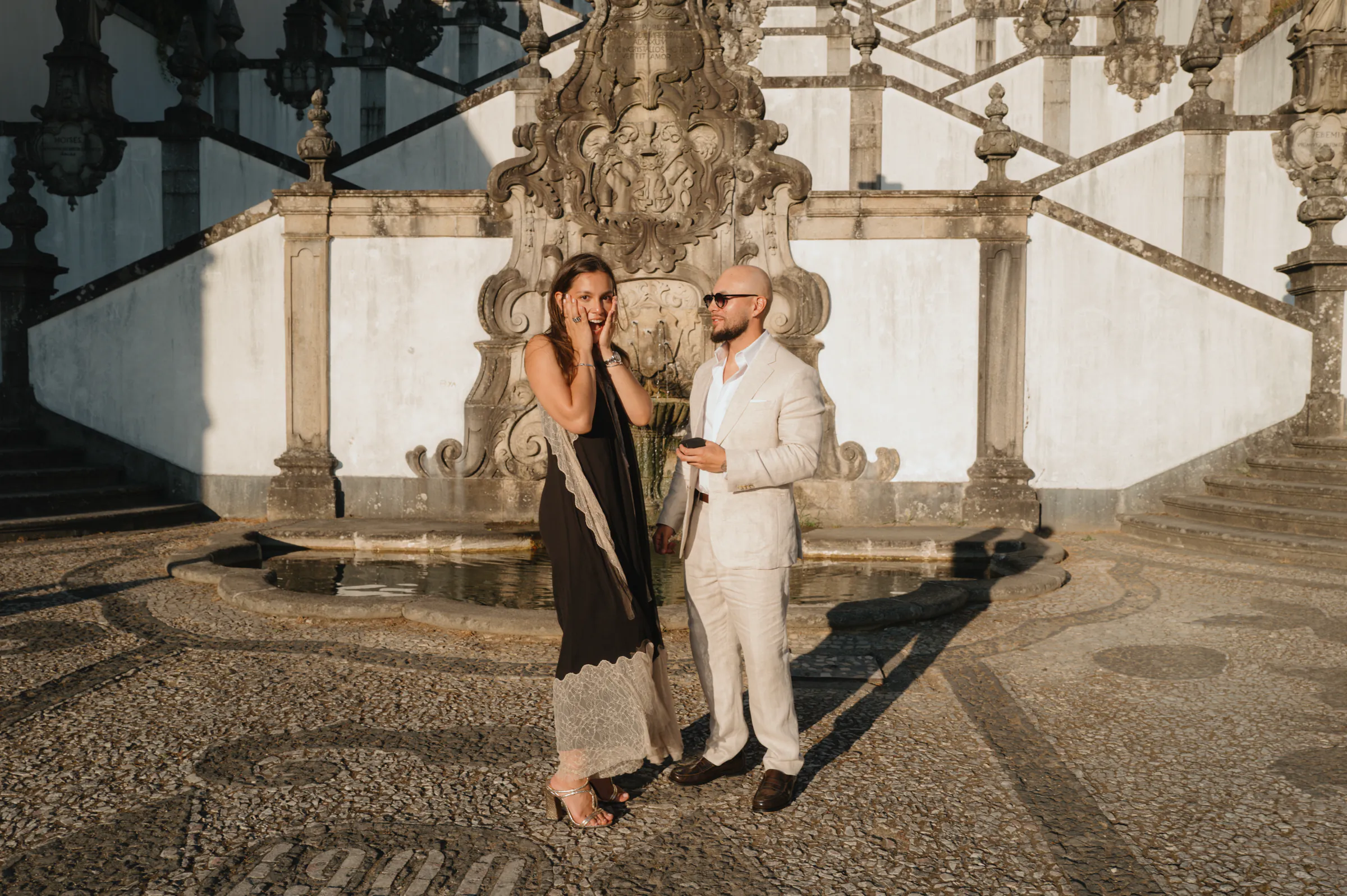 Couple portrait in soft light beside an ornate historic staircase during an outdoor city walk session.