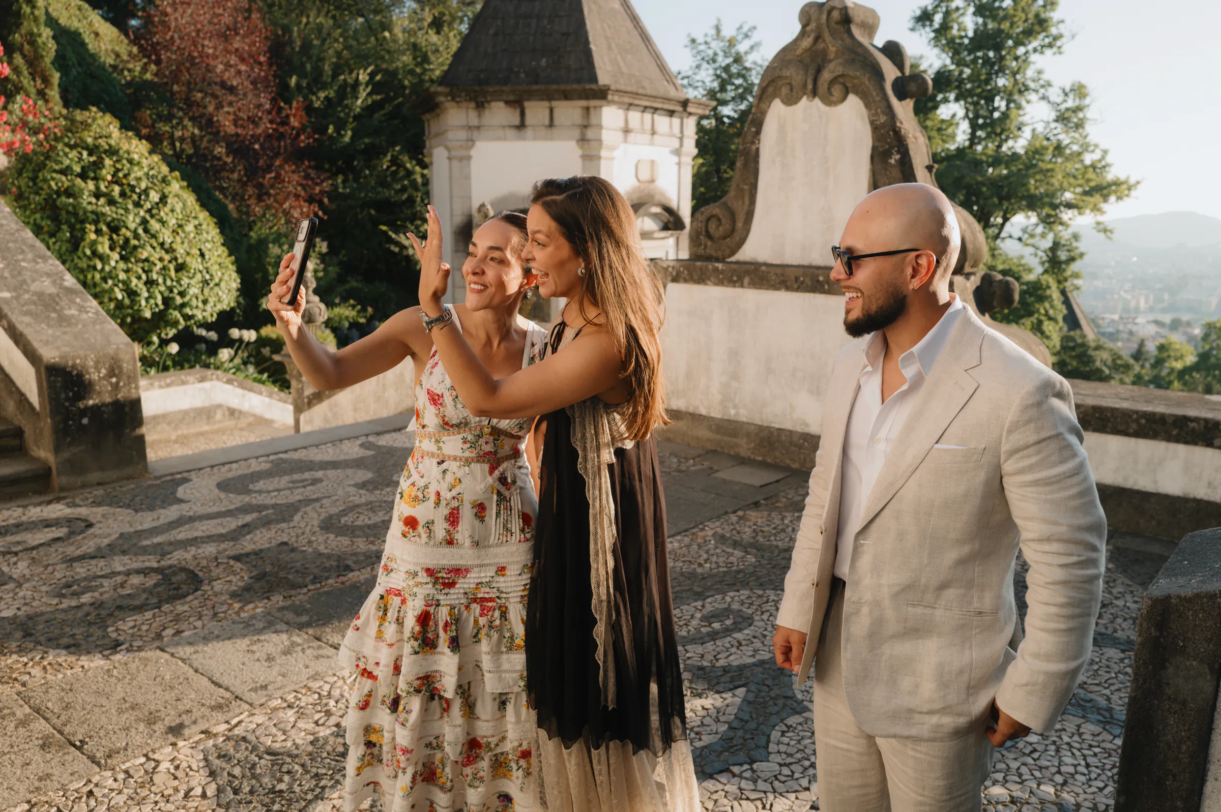 Three adults on a sunlit terrace during an outdoor session, one holding a phone for a selfie.