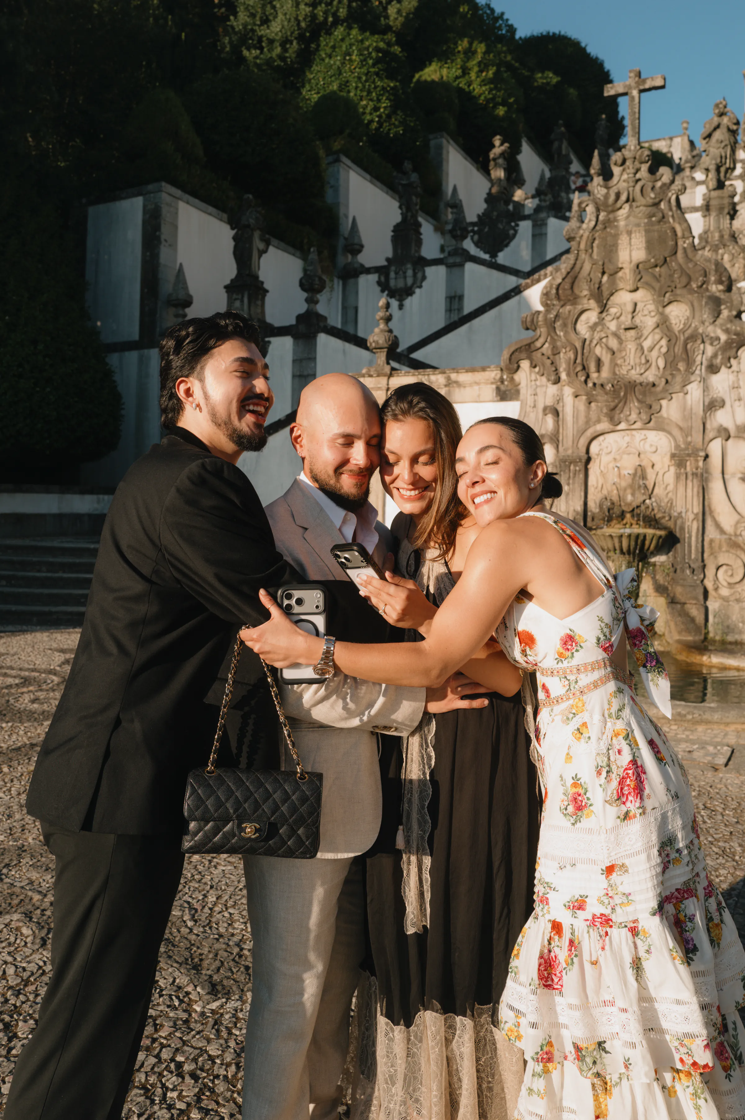Group portrait of four adults during an outdoor session beside an ornate fountain in soft light.