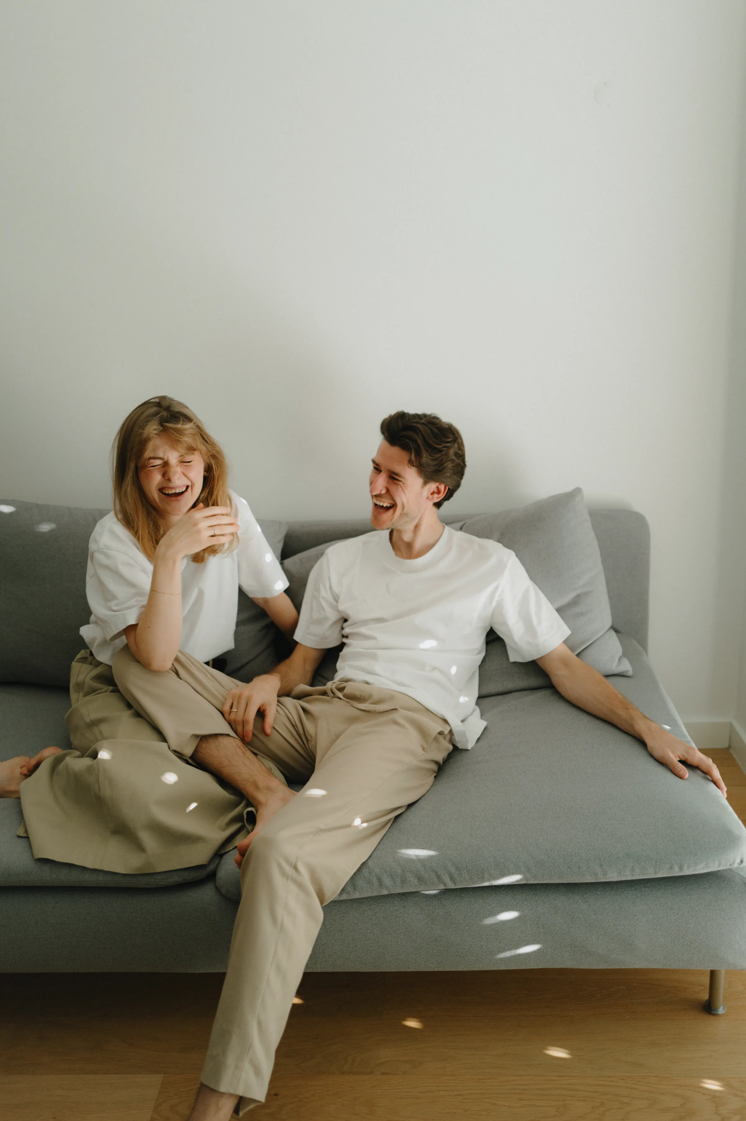 Couple portrait on a gray sofa during a soft light home session.