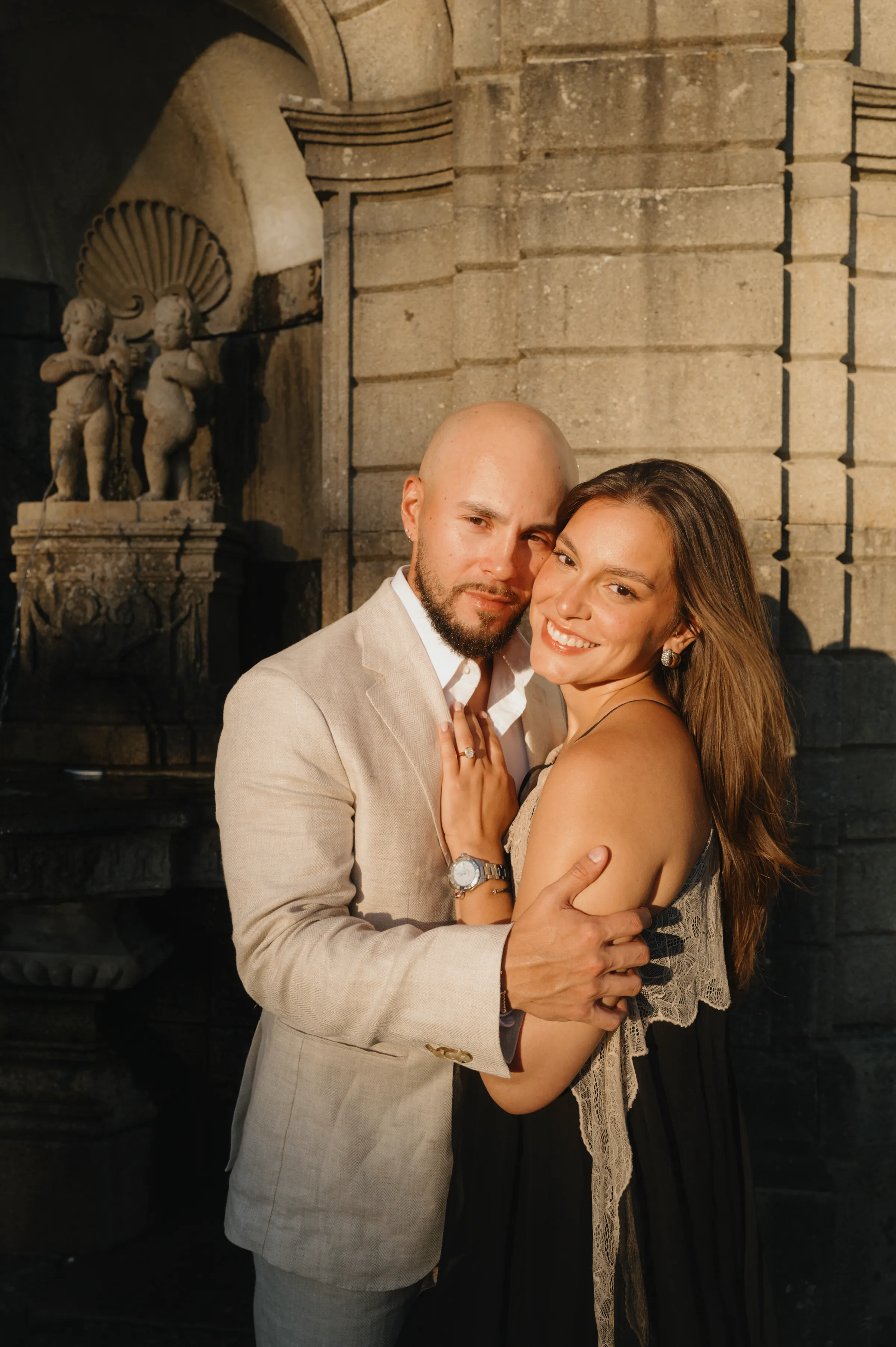 Couple portrait in soft light beside ornate stone architecture during an outdoor session.