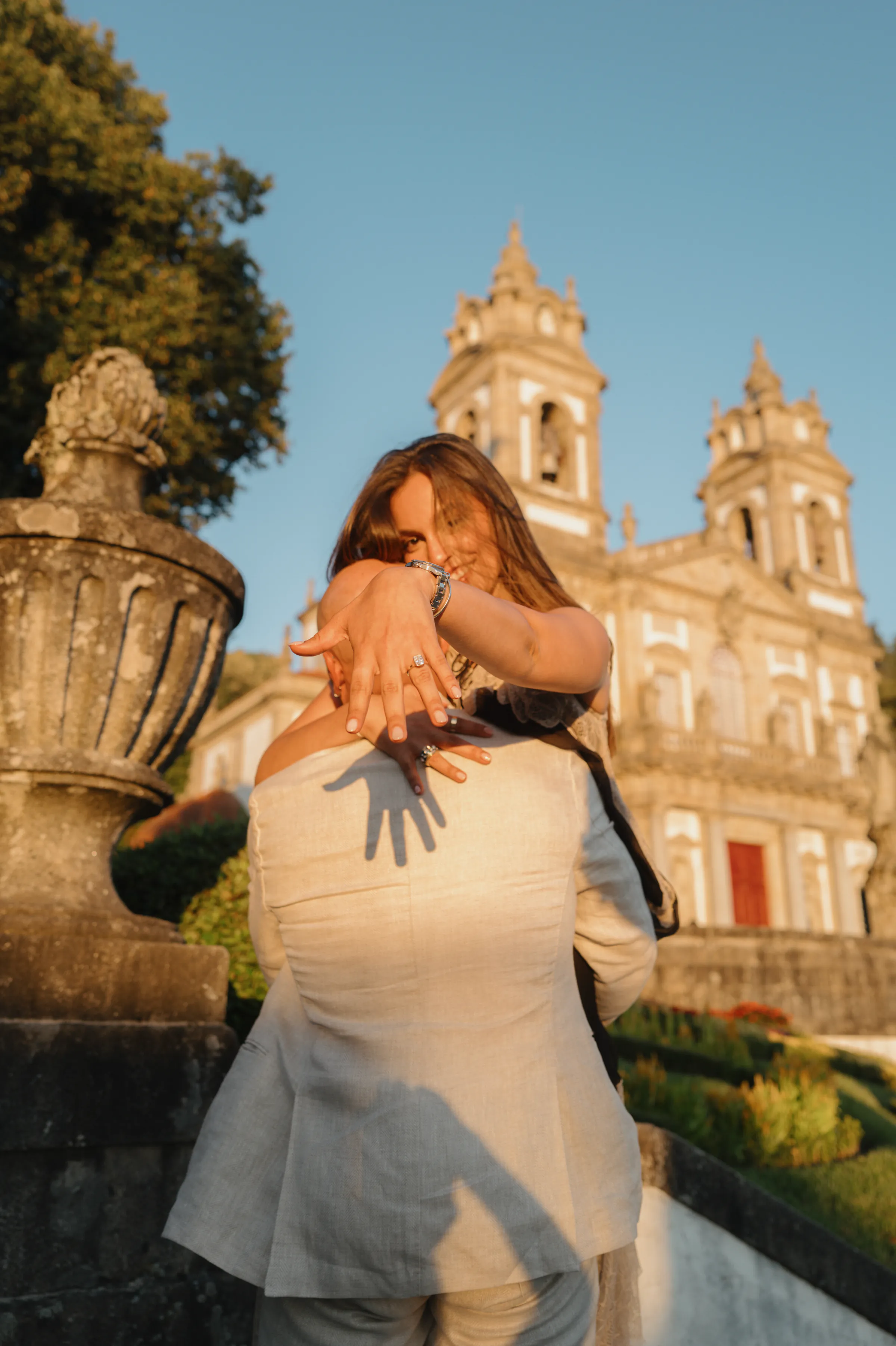 Couple embracing during an outdoor session in soft light beside an ornate historic church.