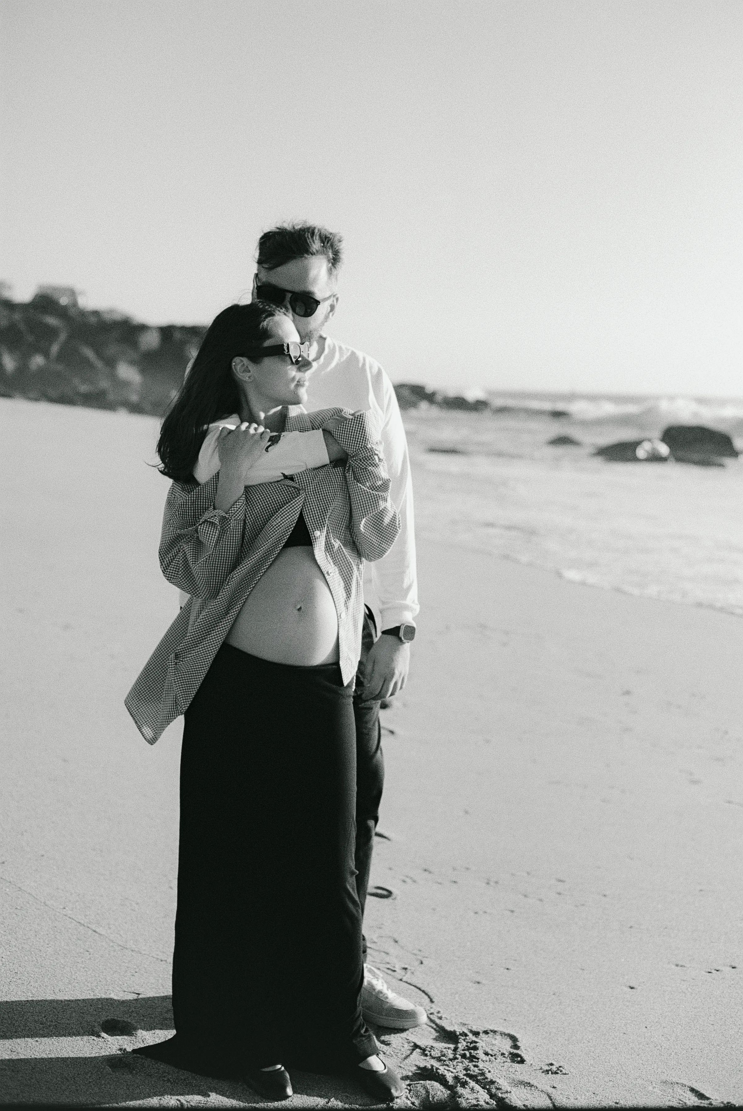 Couple standing together on a sandy beach during a soft light seaside portrait session
