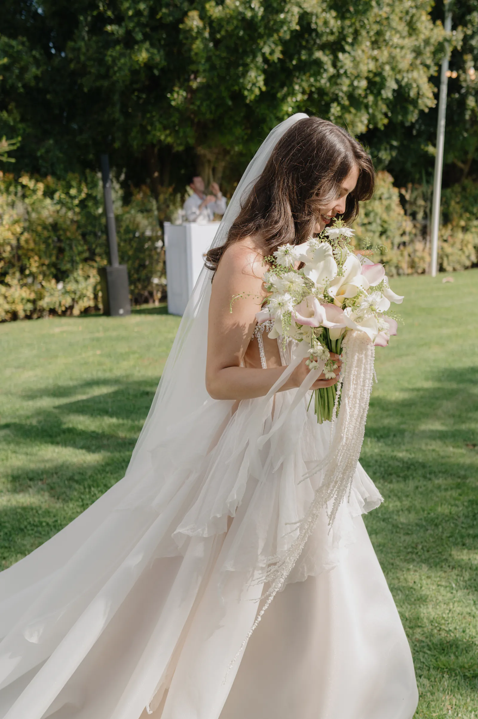 Bride carrying her bouquet through the garden after the ceremony